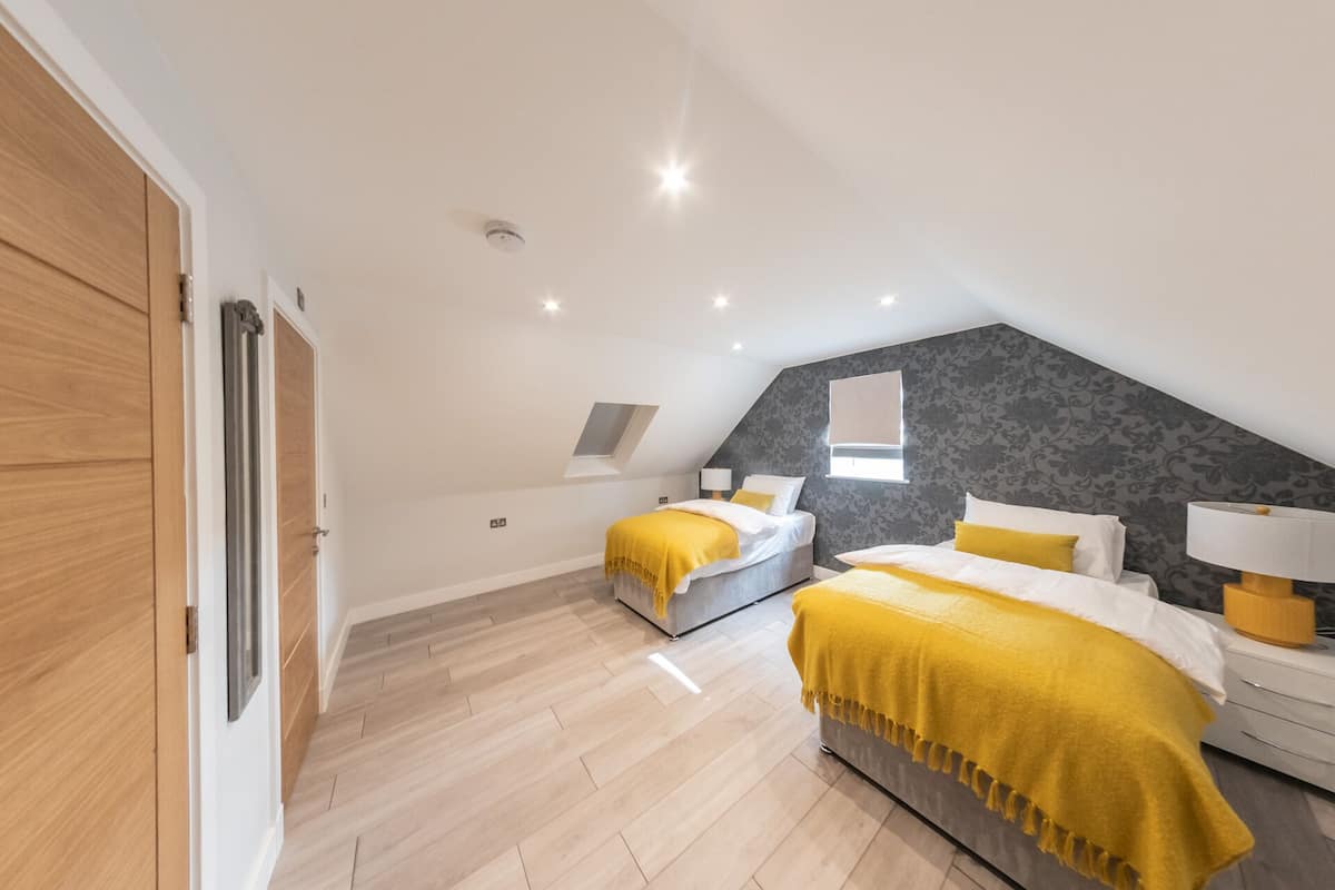 A bedroom with two beds, a skylight, and a modern design.
