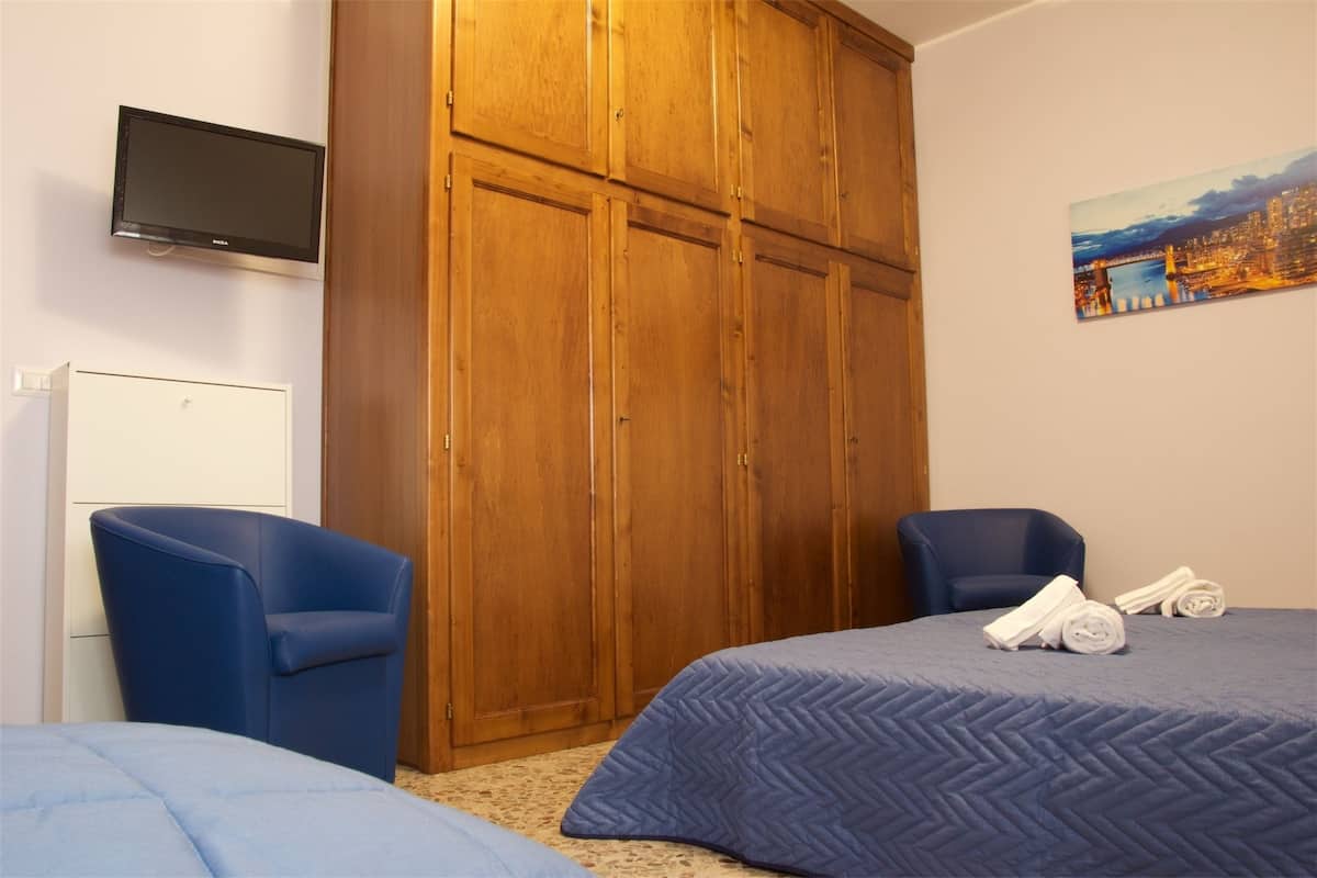 Een hotelkamer met een grote houten garderobe, een flatscreen televisie, twee blauwe stoelen en een bed met een blauwe sprei.