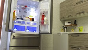 Eine Küche mit einem Edelstahl-Kühlschrank, Holzschränken und einer kleinen Arbeitsfläche mit Kaffeemaschine und Wasserkocher.