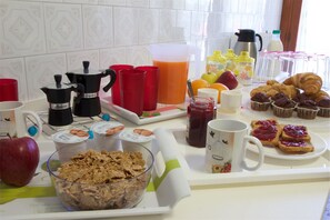 Une table de petit-déjeuner avec divers aliments, notamment des croissants, de la confiture et des céréales.