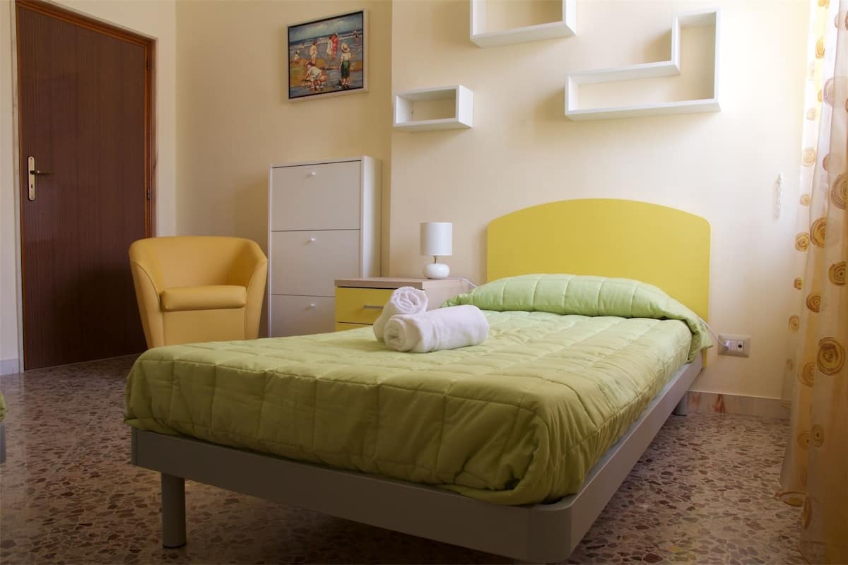 Een hotelkamer met een bed, een stoel, een bureau en een kledingkast.