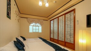 A traditional Japanese-style bedroom with tatami flooring, a shoji screen door, and a futon bed. - Meiden (Wujie)