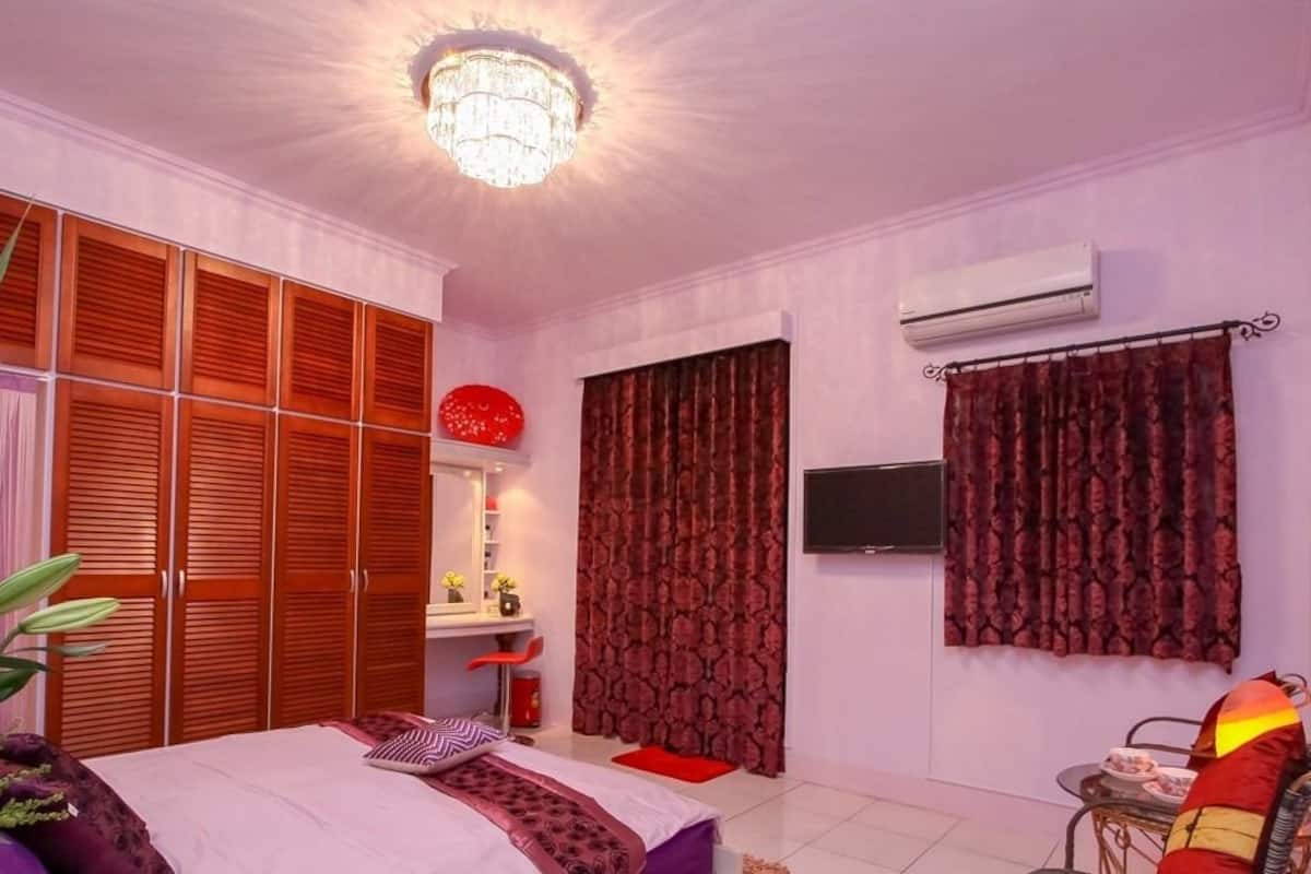 A bedroom with a bed, a desk, a chair, a TV, and a wardrobe.