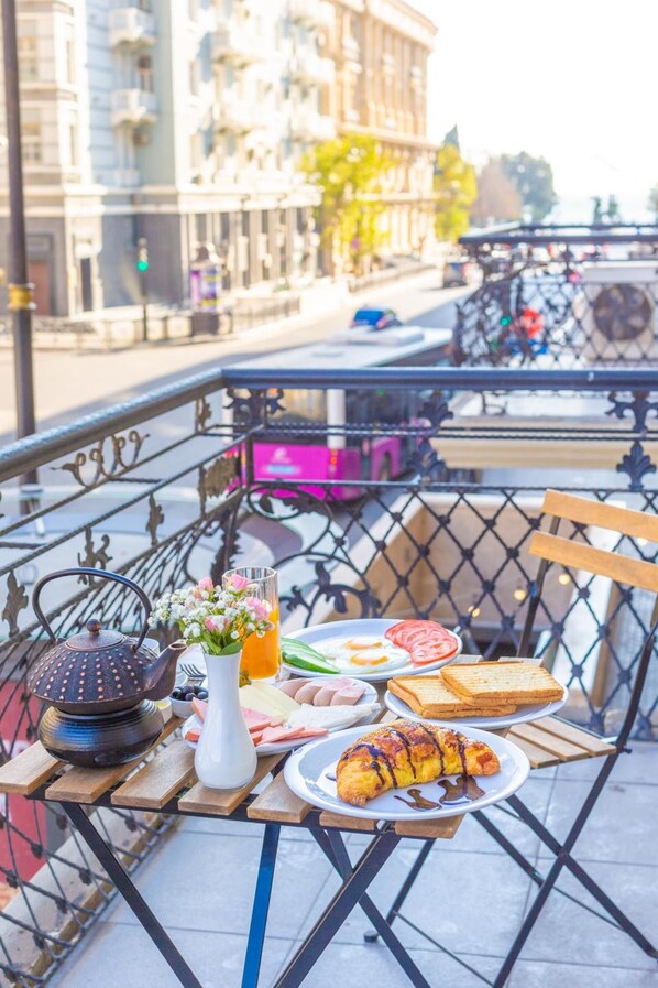 A table with breakfast items on a balcony overlooking a city street.