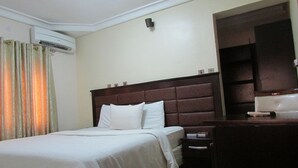 Una habitación de hotel con una cama grande, una mesita de noche, un escritorio y un armario.
