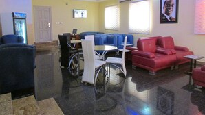 Un hall de hotel con zona de estar, refrigerador y televisor.