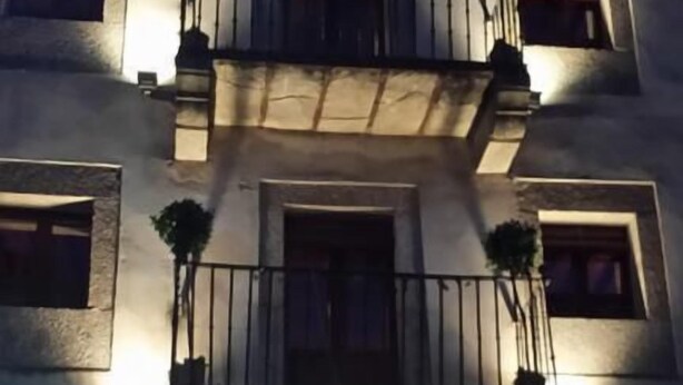 A building with a central entrance, multiple windows, and balconies with plants.
