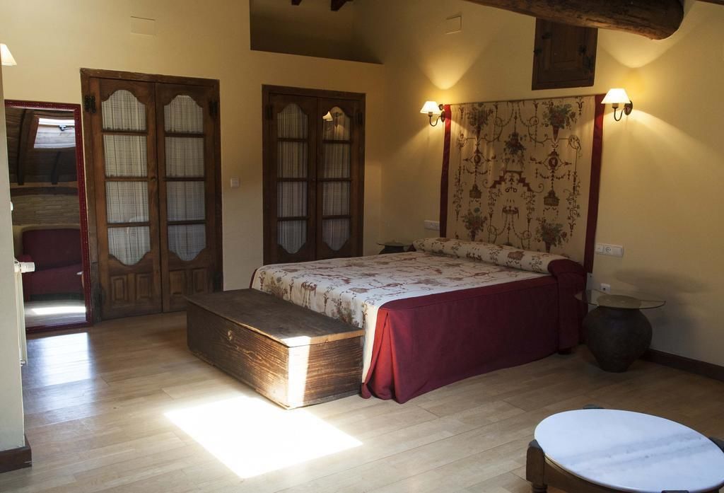 Un dormitorio con cama, banca, mesa redonda y armario.