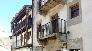 A narrow street with traditional buildings, a bench, and potted plants.