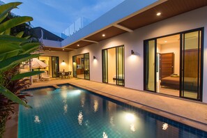 Un área de piscina moderna con vistas despejadas a la piscina, una zona de estar techada y un dormitorio con puertas de cristal correderas.