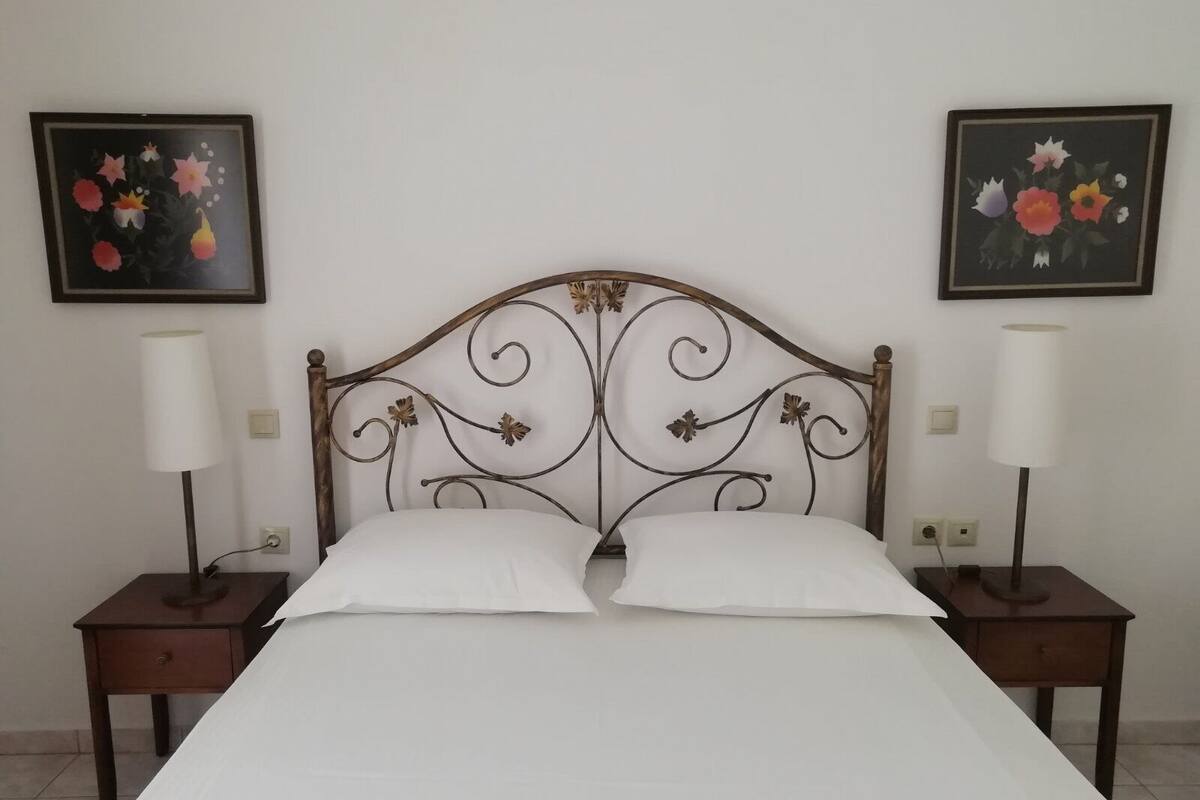 A bed with a metal headboard, two bedside tables, and two lamps.