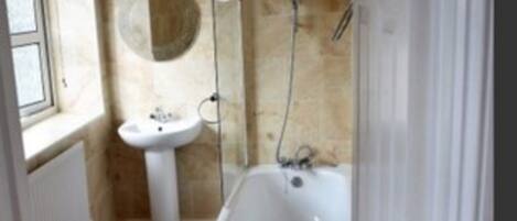 A narrow bathroom with a bathtub, a sink, and a mirror.