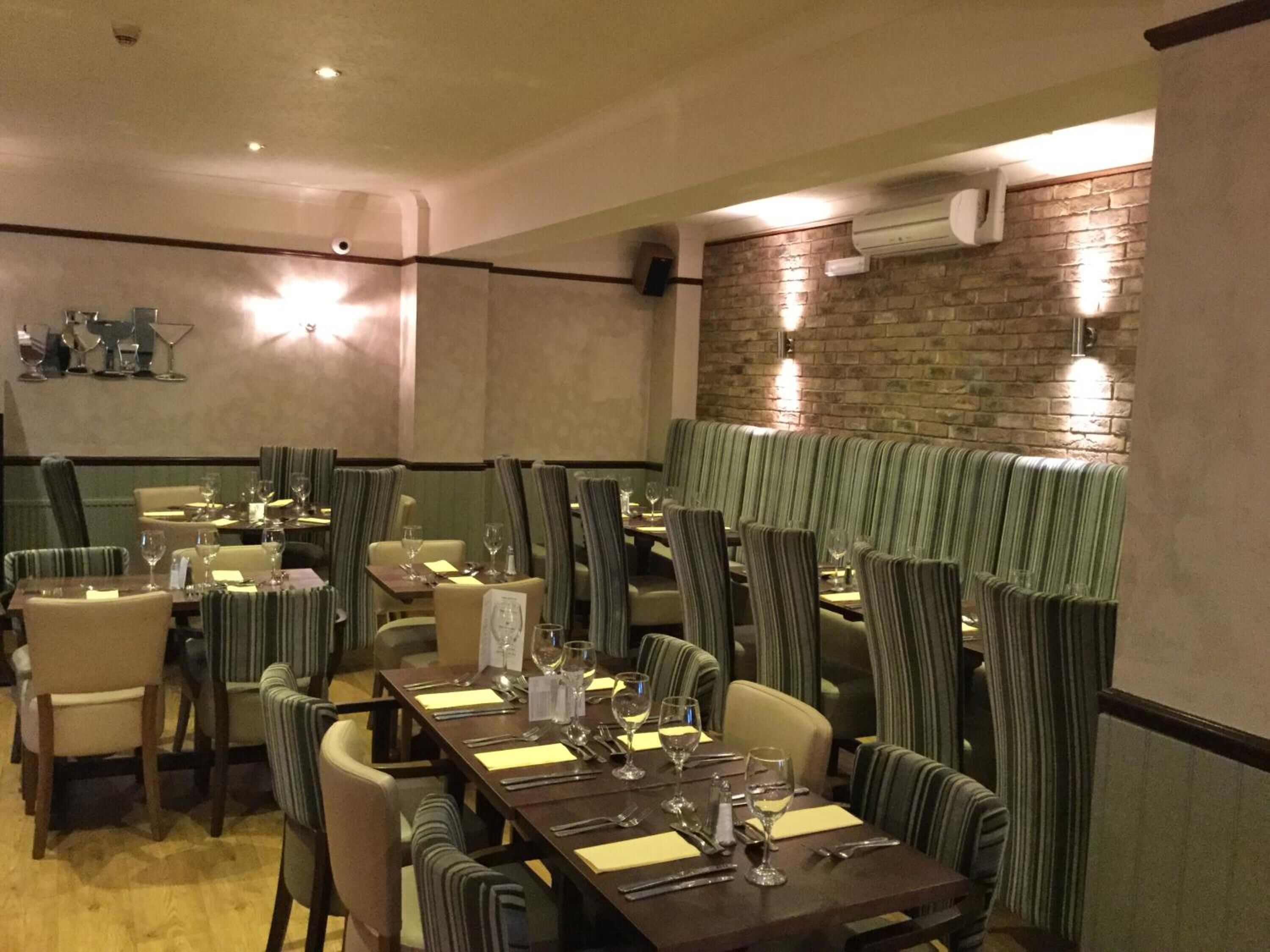 Un restaurante con sillas y mesas a rayas, una pared de ladrillo y un equipo de aire acondicionado.