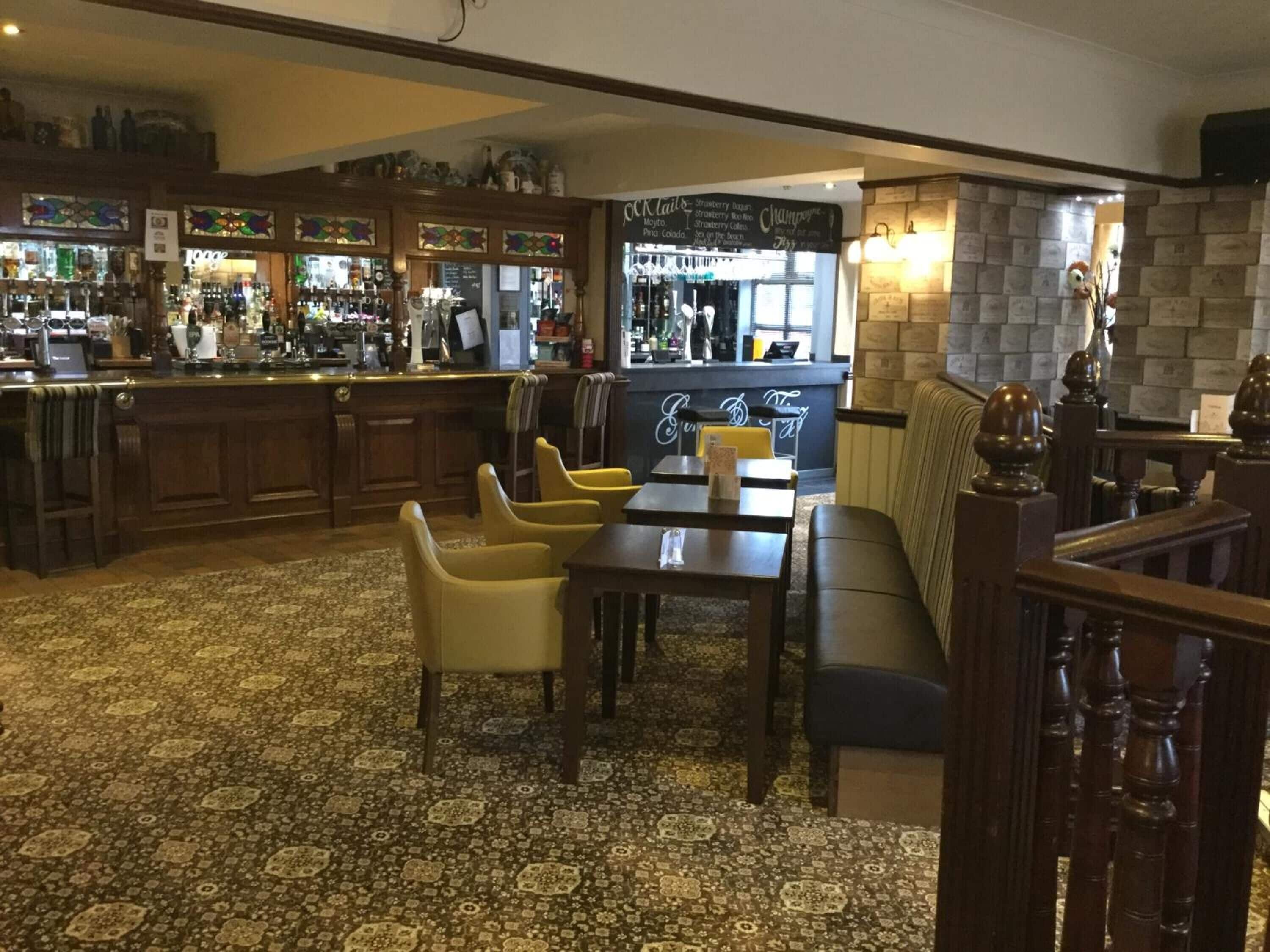 Un'area bar con arredi in legno, una moquette decorata e un muro in pietra.