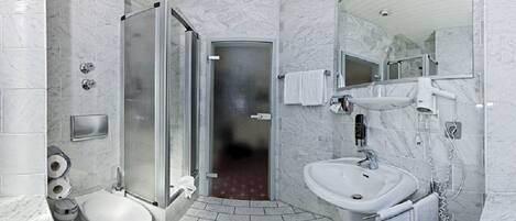 Un baño moderno con cabina de ducha de vidrio, un lavabo blanco y un inodoro.