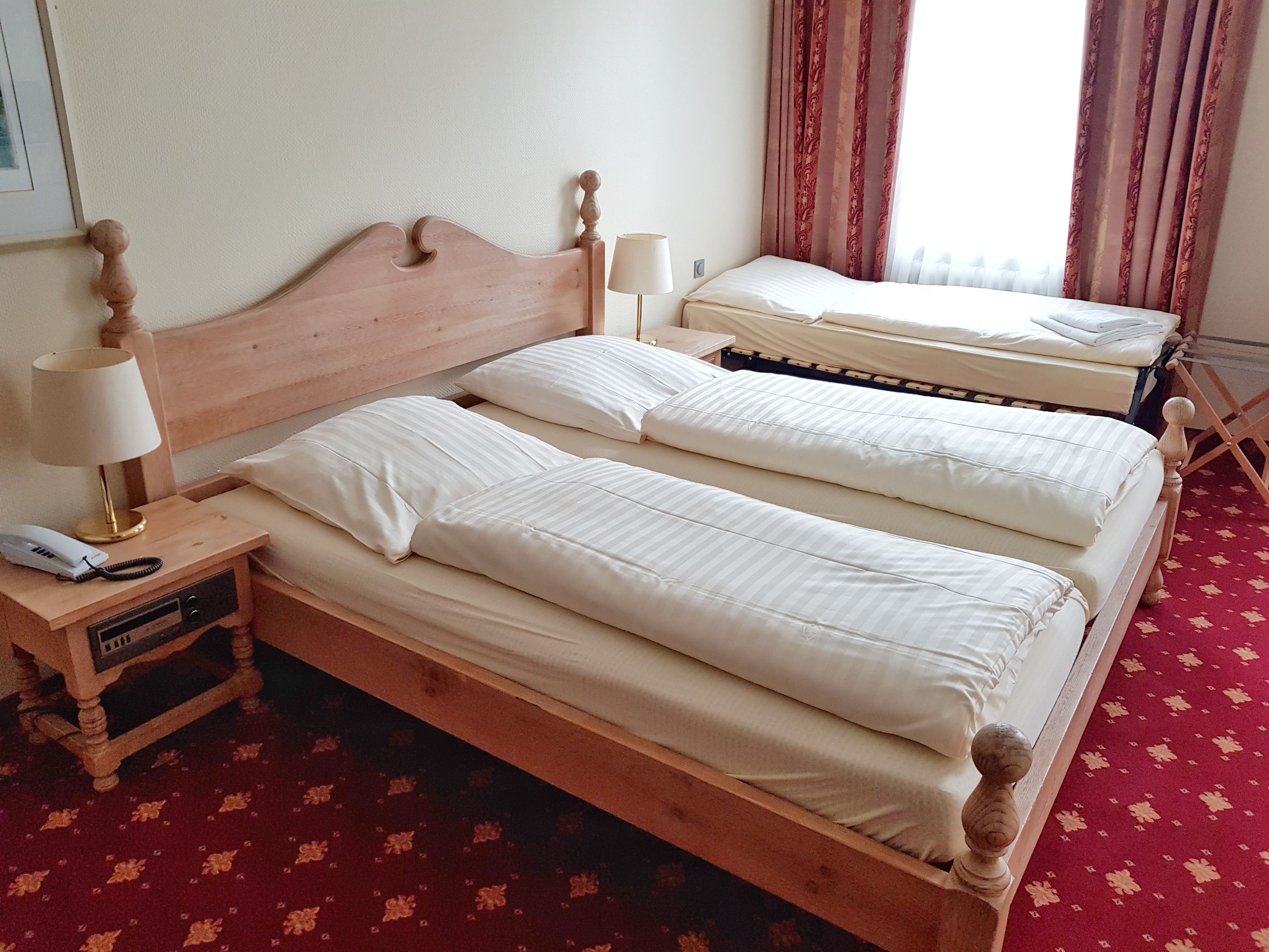 A double bed with a wooden headboard, a bedside table with a lamp, and a phone.