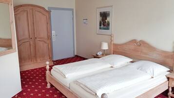 Une chambre avec un lit double, une armoire en bois, une table de chevet avec une lampe et une porte.