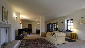 Amplia sala de estar con un tapete grande, un sofá, una chimenea y un piano al fondo.