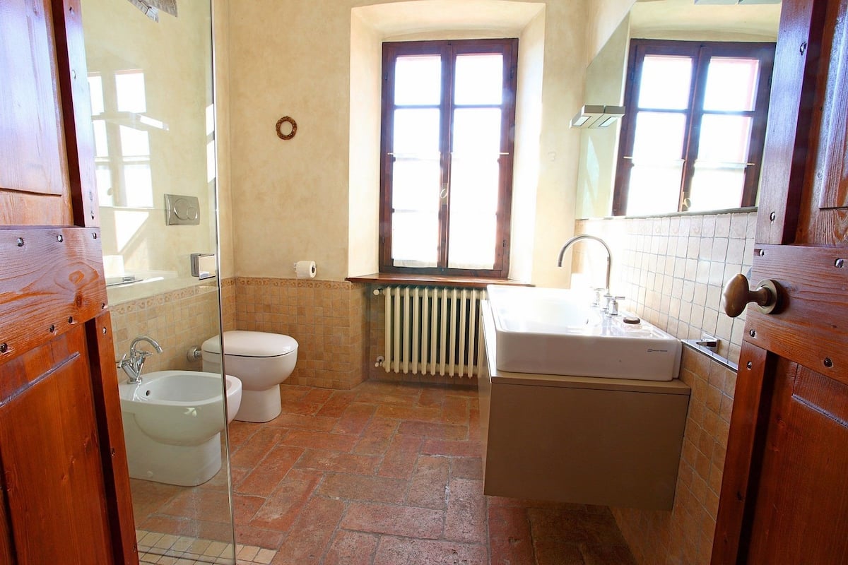 Een badkamer met toilet, bidet, wastafel en een raam.