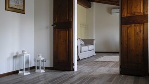 Una habitación con una puerta de madera, un sofá blanco y dos faroles blancos en el suelo.