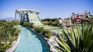 Een waterpark met een glijbaan, een zwembad en veel groen eromheen.