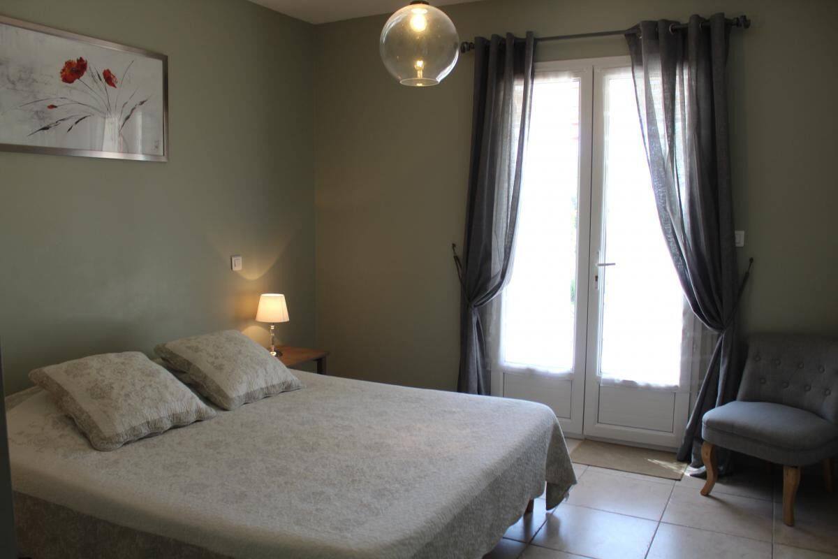 Une chambre à coucher avec un lit, une chaise, une lampe et une porte avec des rideaux.