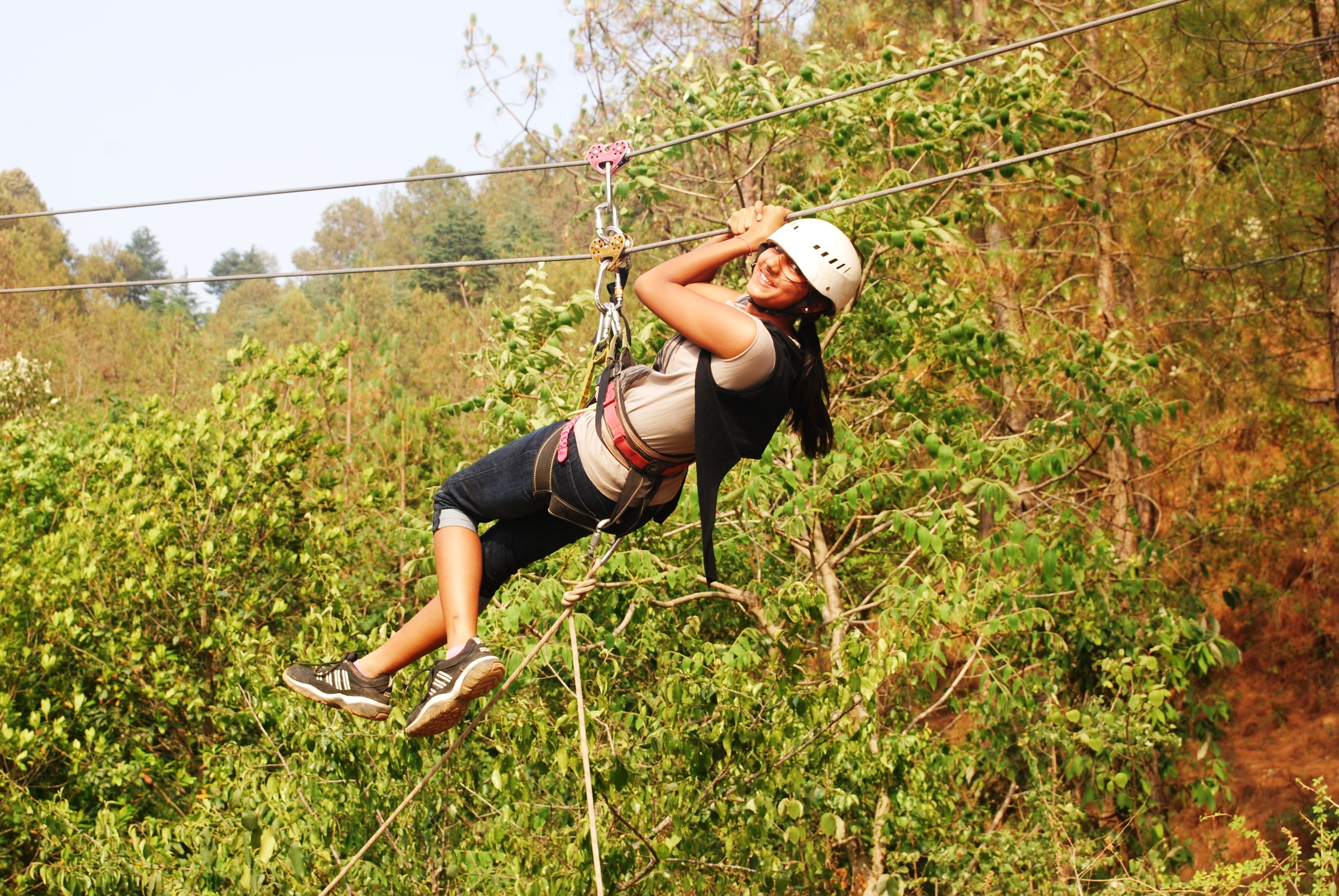 A person zip-lining through a forested area.