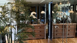 Un intérieur moderne agrémenté d’un grand miroir, de meubles en osier et d’une plante en pot.