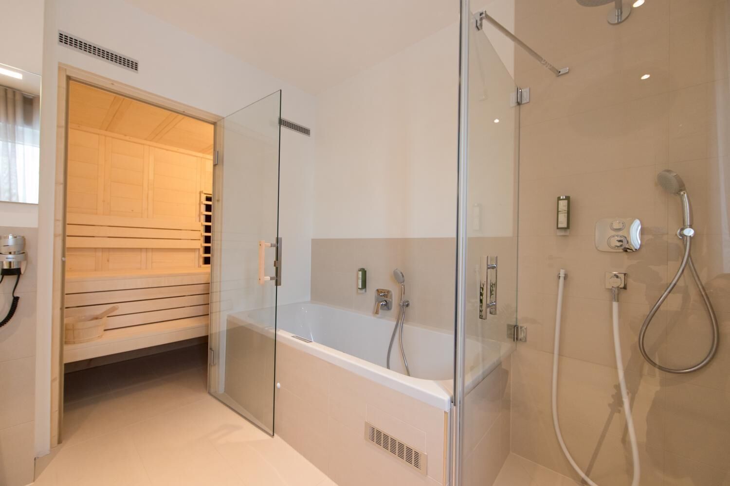 Un baño moderno con ducha envuelta en vidrio, bañera y sauna de madera.
