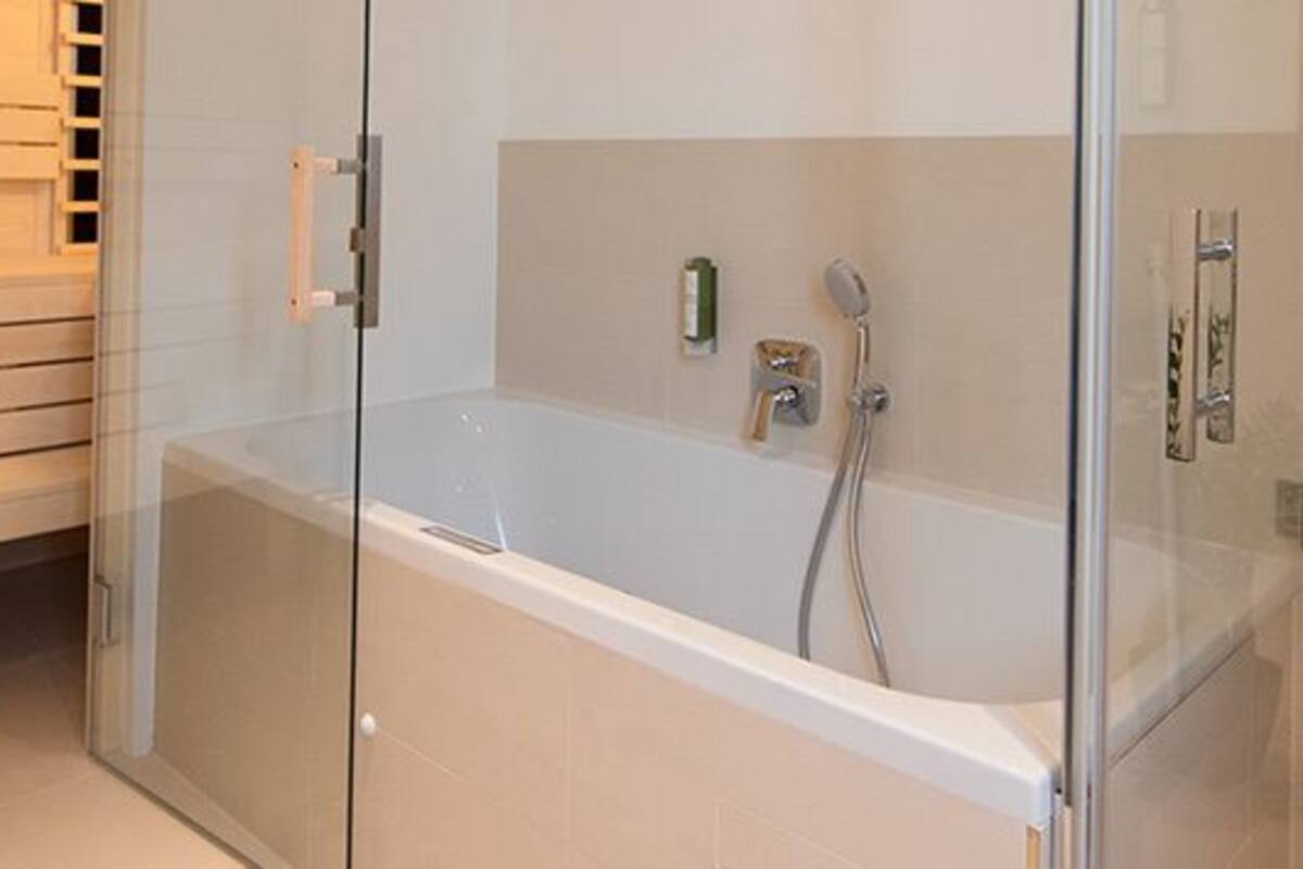 A modern bathroom with a glass-enclosed shower, a white bathtub, and a toilet.