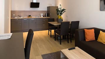 A modern living room with a sofa, a dining table, and a kitchen area in the background.