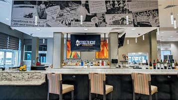 Zona de bar con barra, taburetes y una pantalla de televisión que muestra 'STREETLIGHT KITCHEN & BAR'.