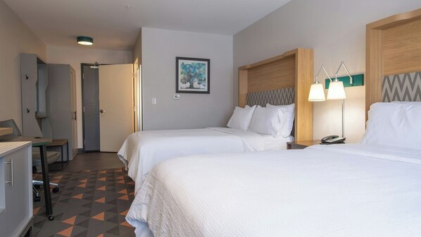 A hotel room with two beds, a desk, a chair, a phone, and a painting on the wall.