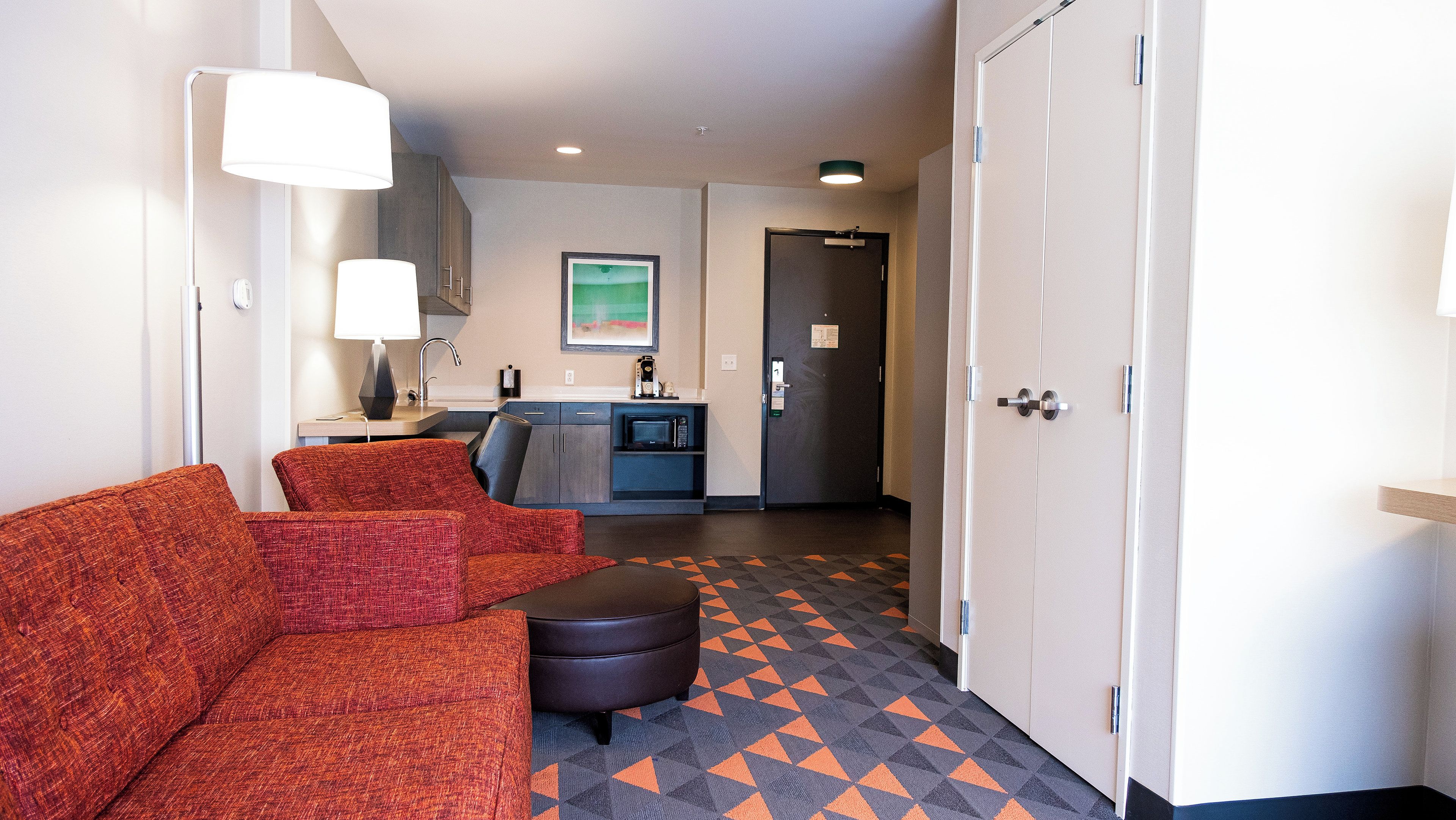 Habitación de hotel con sofá, una mesita, microondas y pequeña cocina.