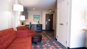 A hotel room with a sofa, a small table, a microwave, and a kitchenette area. - Holiday Inn & Suites Philadelphia W - Drexel Hill by IHG (Drexel Hill)
