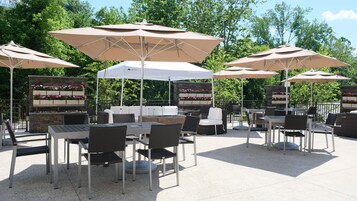 Un patio al aire libre con mesas y sillas, rodeado de grandes sombrillas.