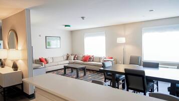 Una sala moderna con sofá, mesa de comedor y zona de cocina.