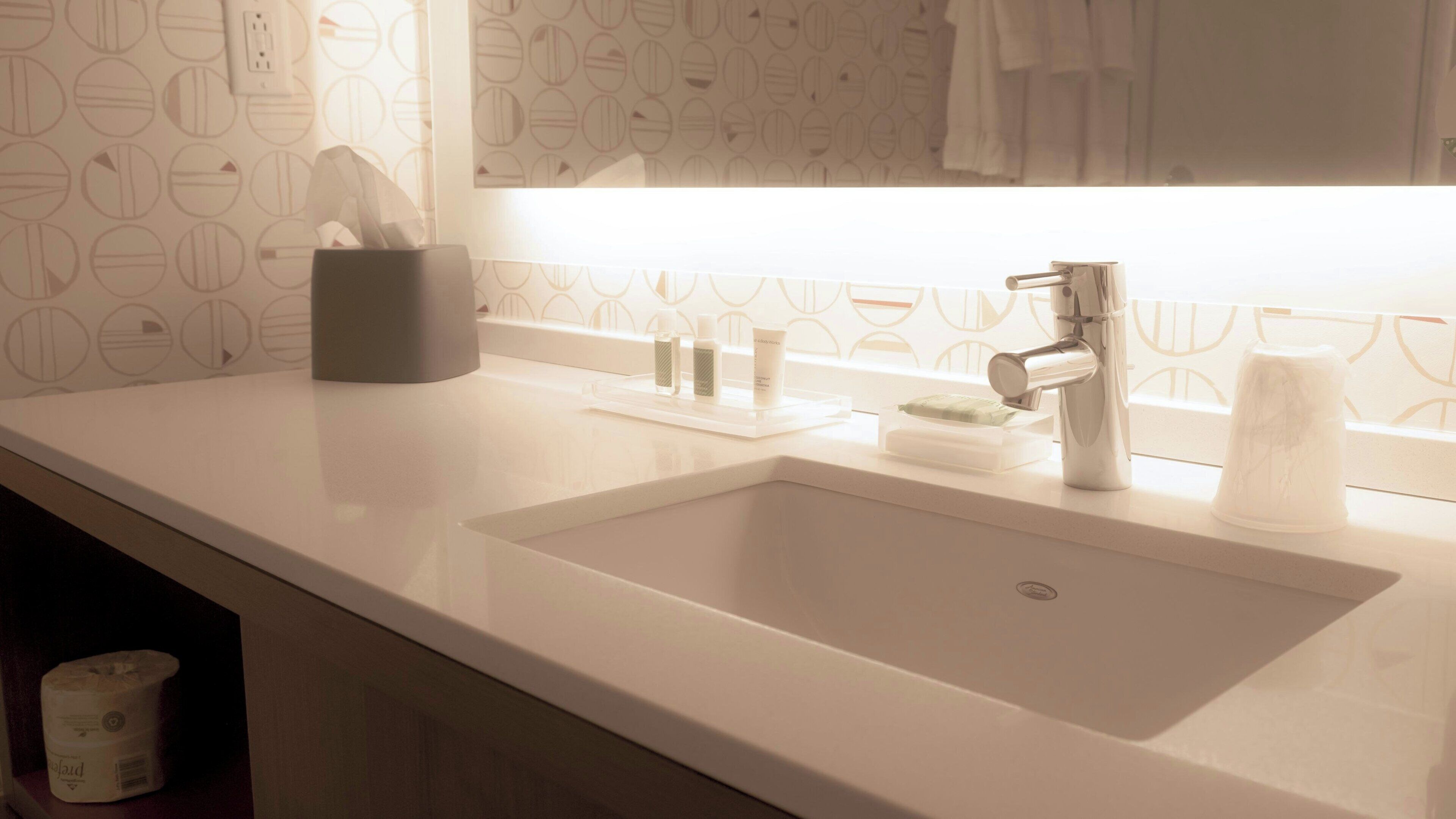 Un baño moderno con un lavamanos blanco, un espejo y un perchero para toallas.