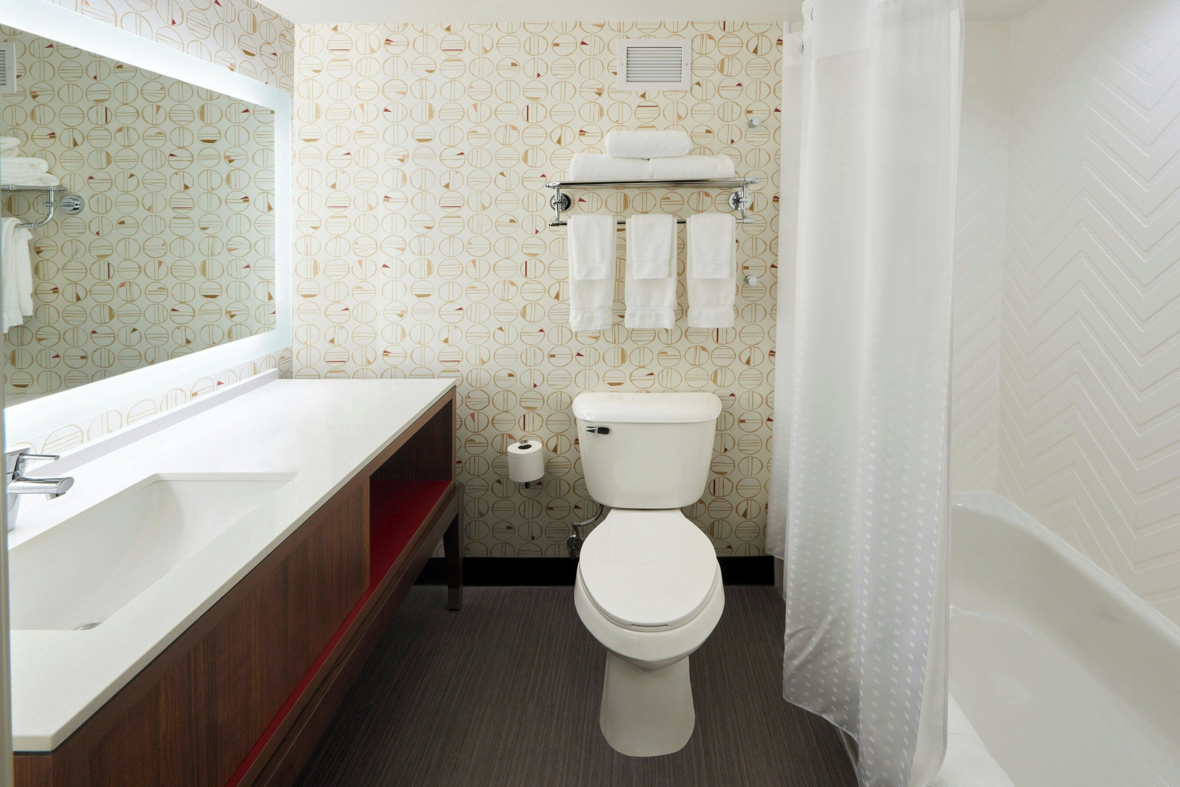 A bathroom with a toilet, a sink, and a mirror.