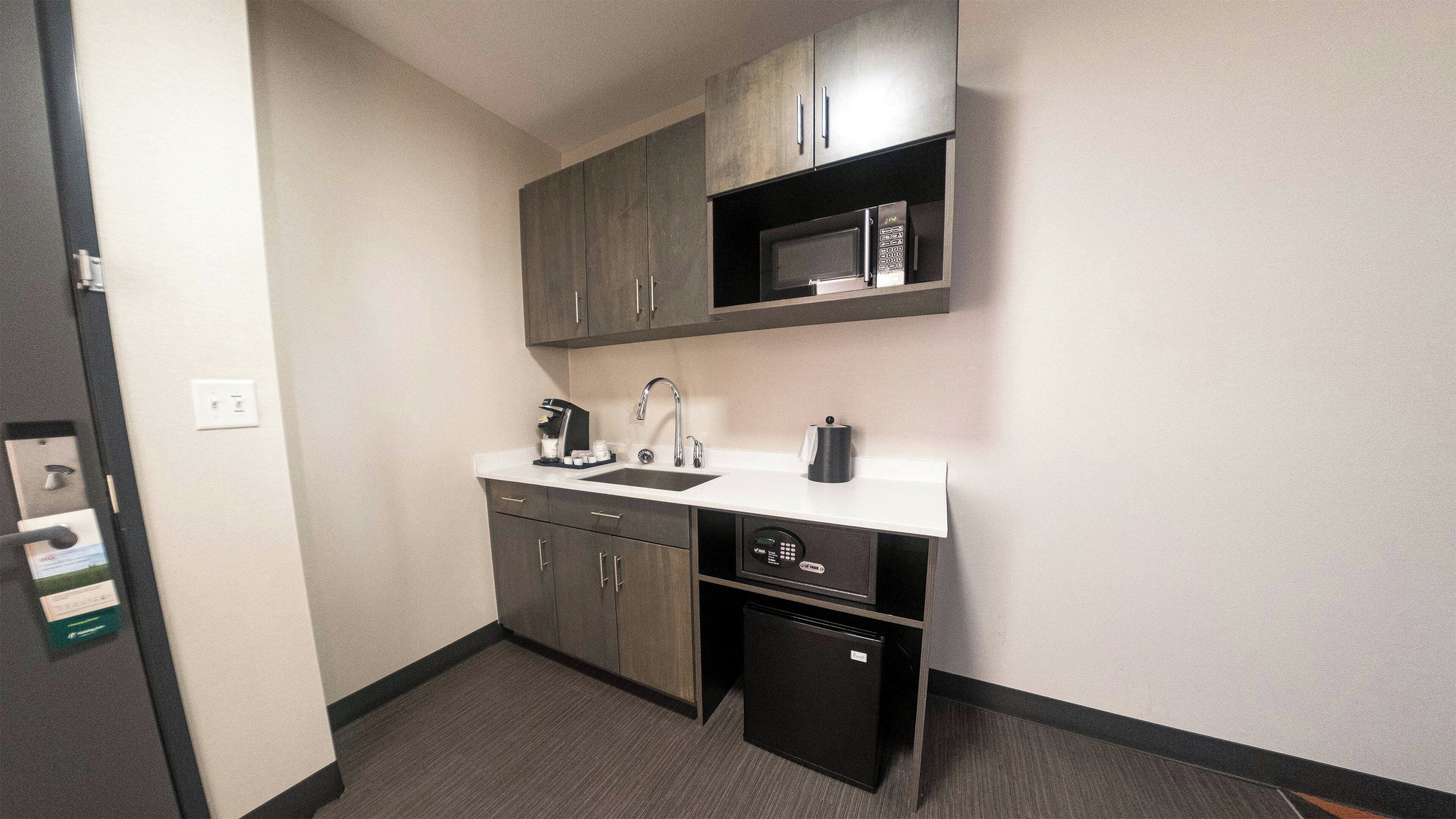 A compact kitchenette with a microwave, coffee maker, and a small refrigerator.