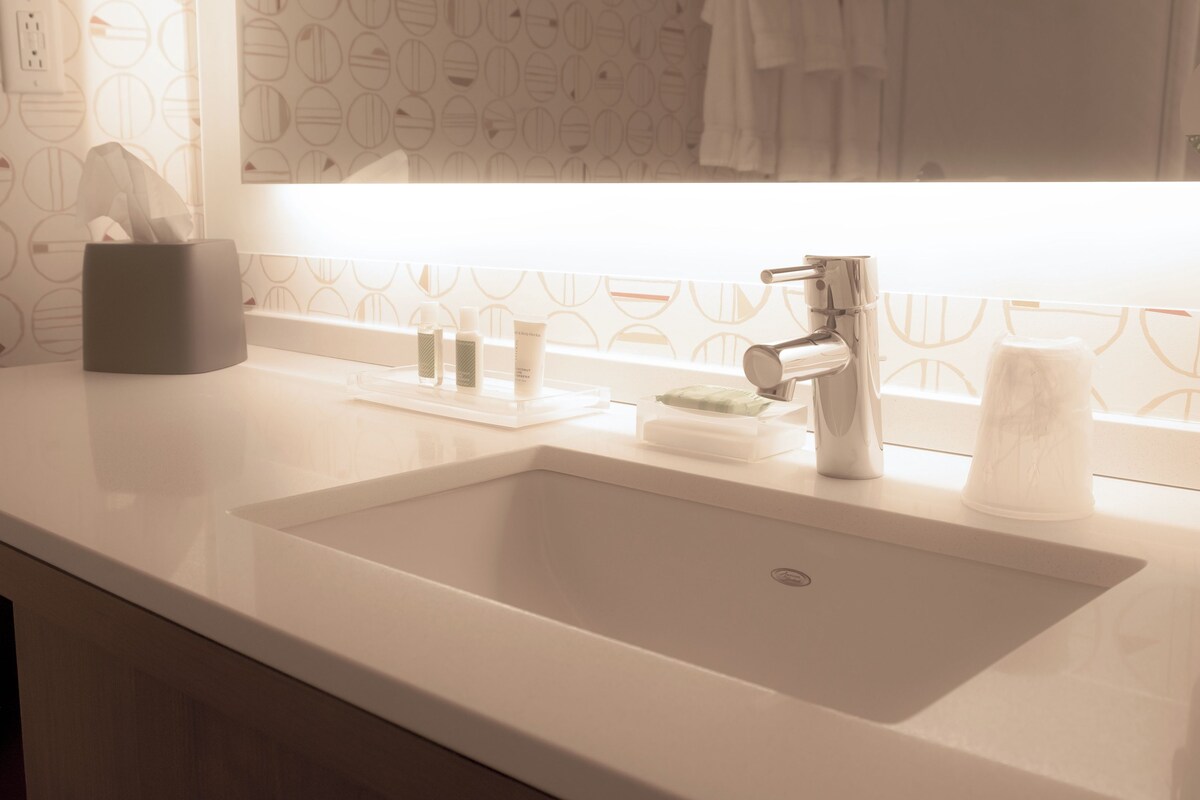 A bathroom with a white sink, a mirror, and a towel rack.