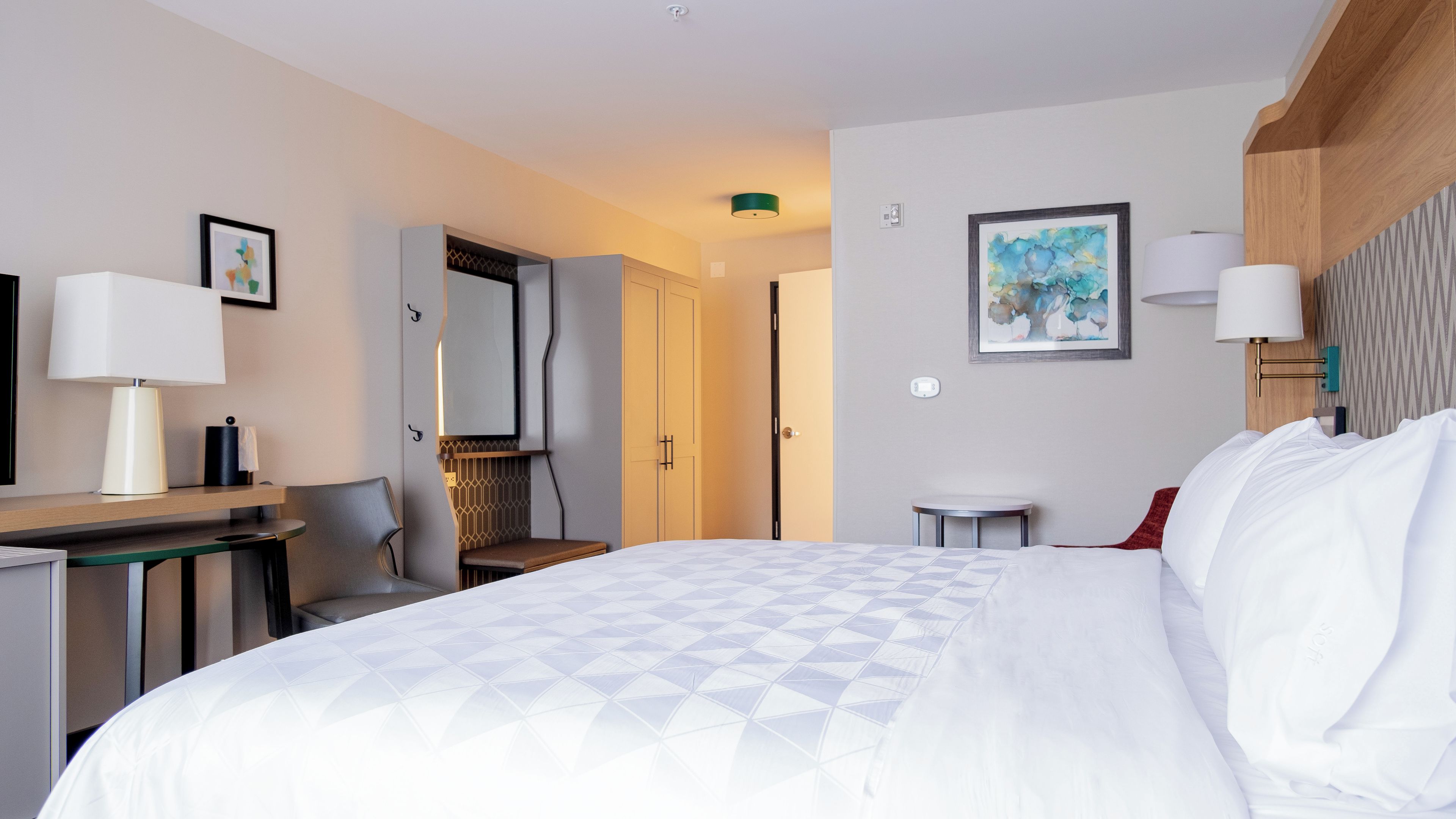 A hotel room with a bed, desk, chair, and a round table.