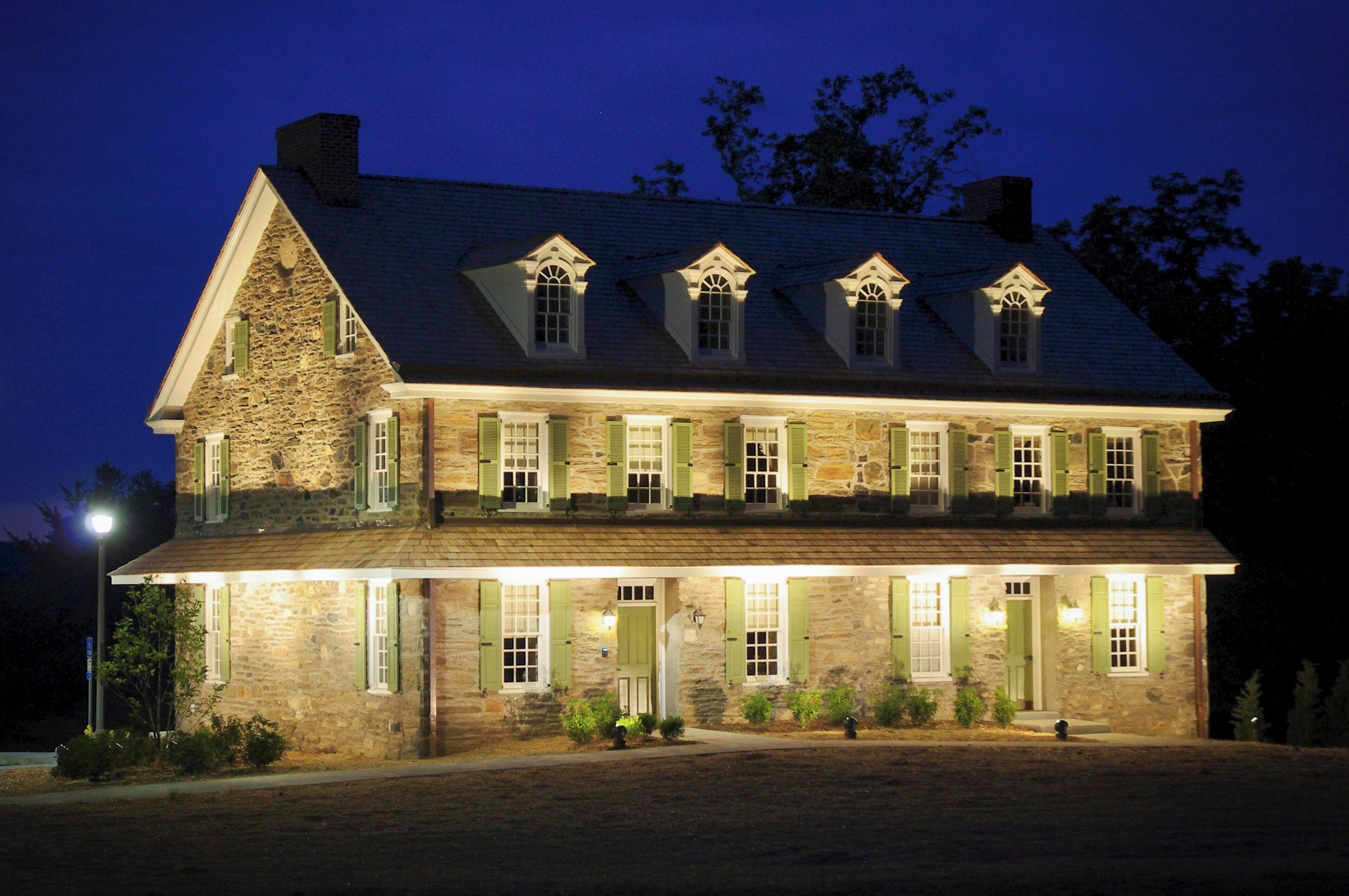A large stone building with multiple windows and a prominent chimney, illuminated at night.