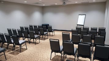 A conference room with rows of chairs, a projector screen, and a carpeted floor.