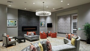 A modern lounge area with a fireplace, comfortable seating, and artwork on the walls. - Holiday Inn & Suites Philadelphia W - Drexel Hill by IHG (Drexel Hill)
