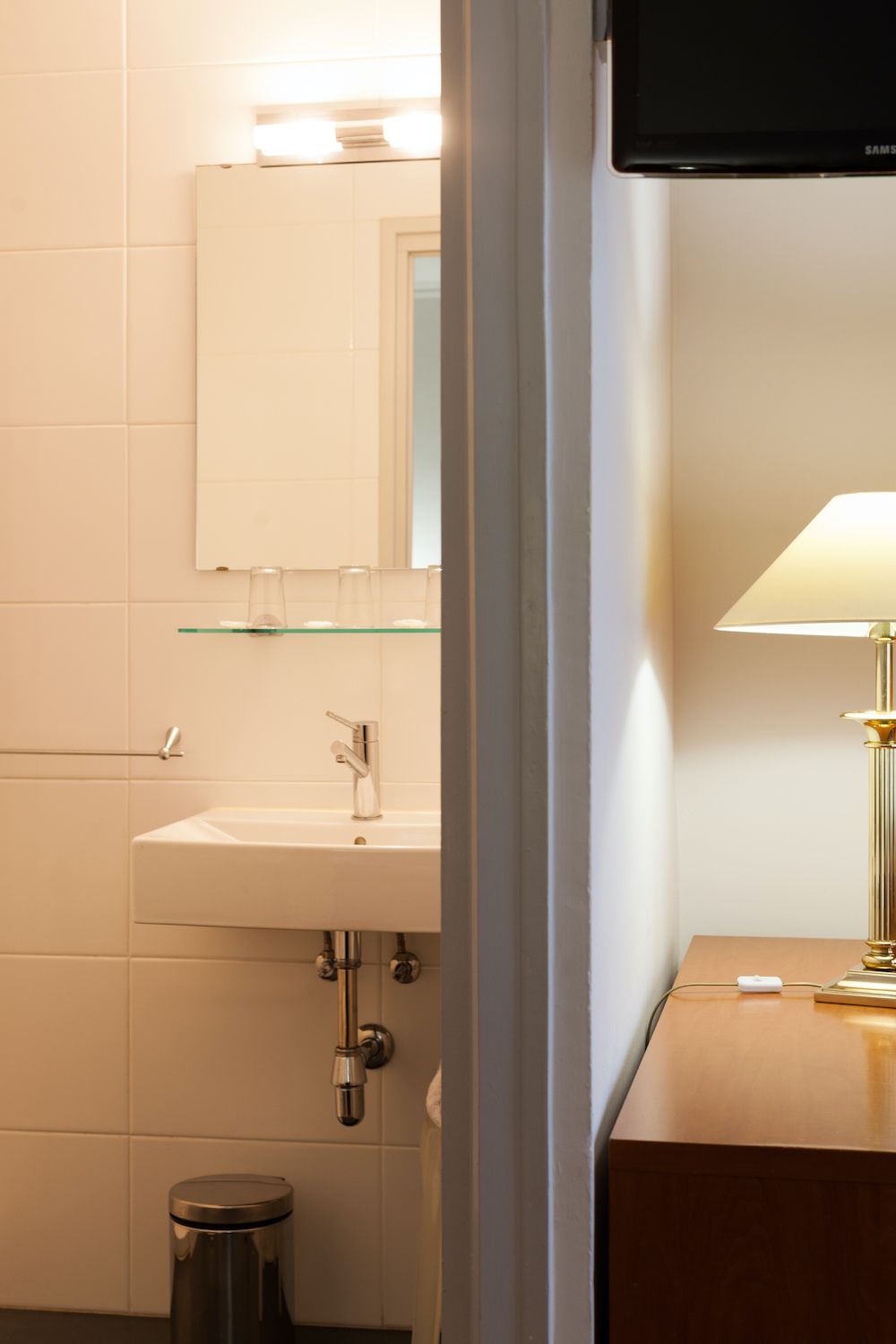 A bathroom with a white sink, mirror, and glass shelves.