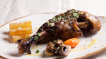 Un plat amb una cuixa de xai rostida, una pastanaga i algunes bolets.