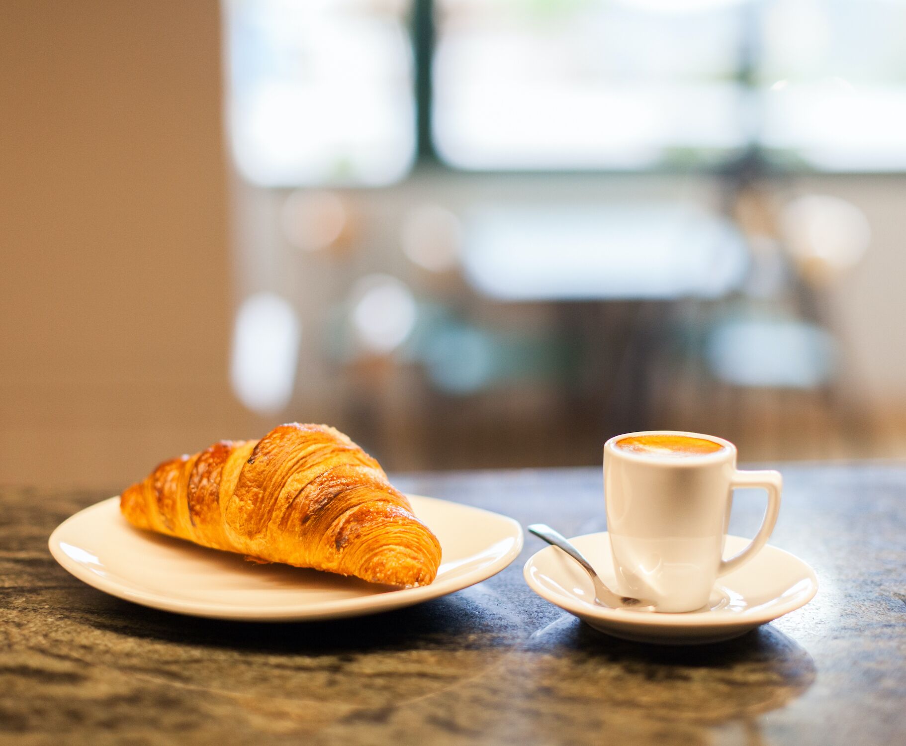 Un croissant e una tazza di caffè su un tavolo in un bar.