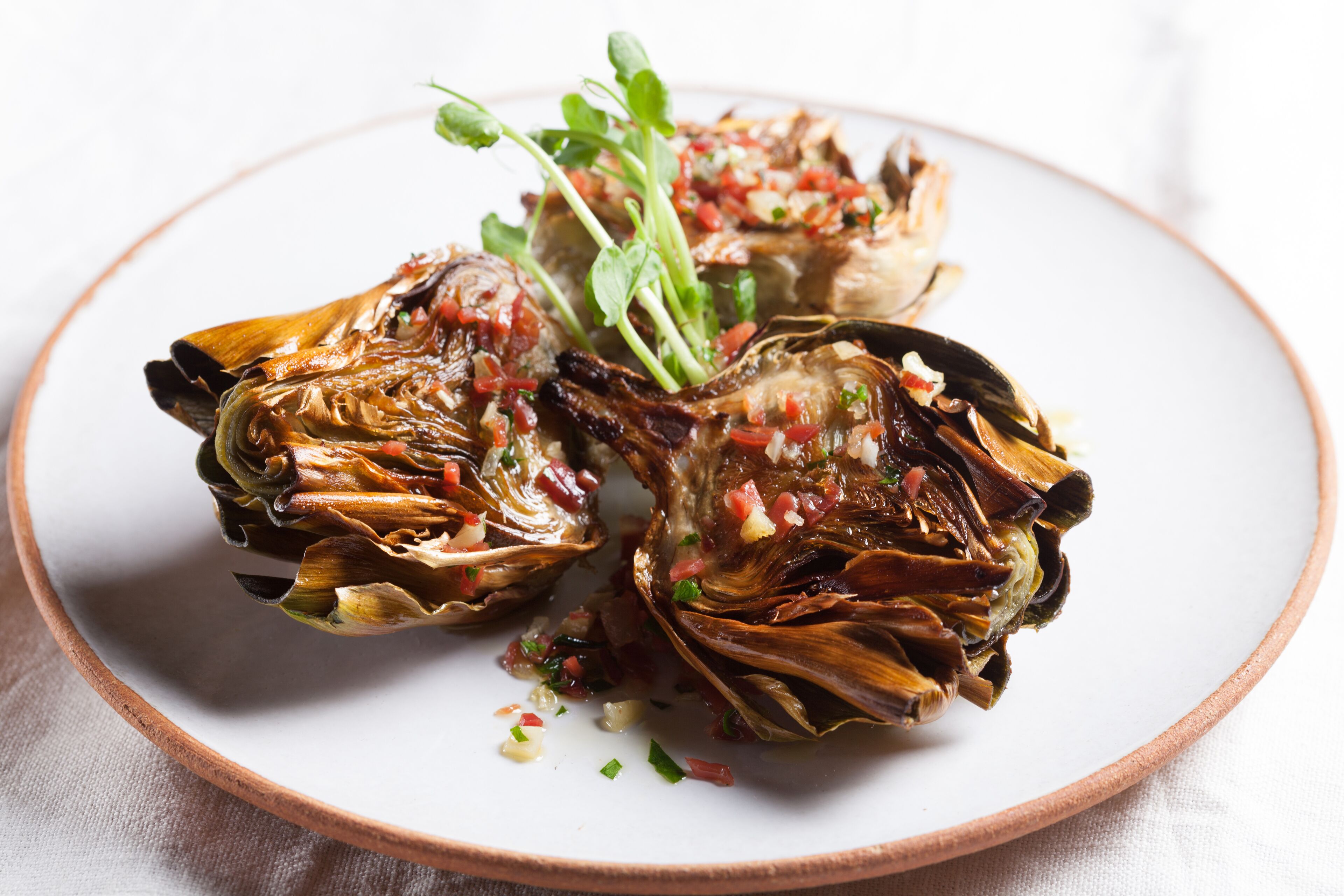Un plat d'anvers de caragols de terra decorat amb herbes aromàtiques i un petit guarniment verd.