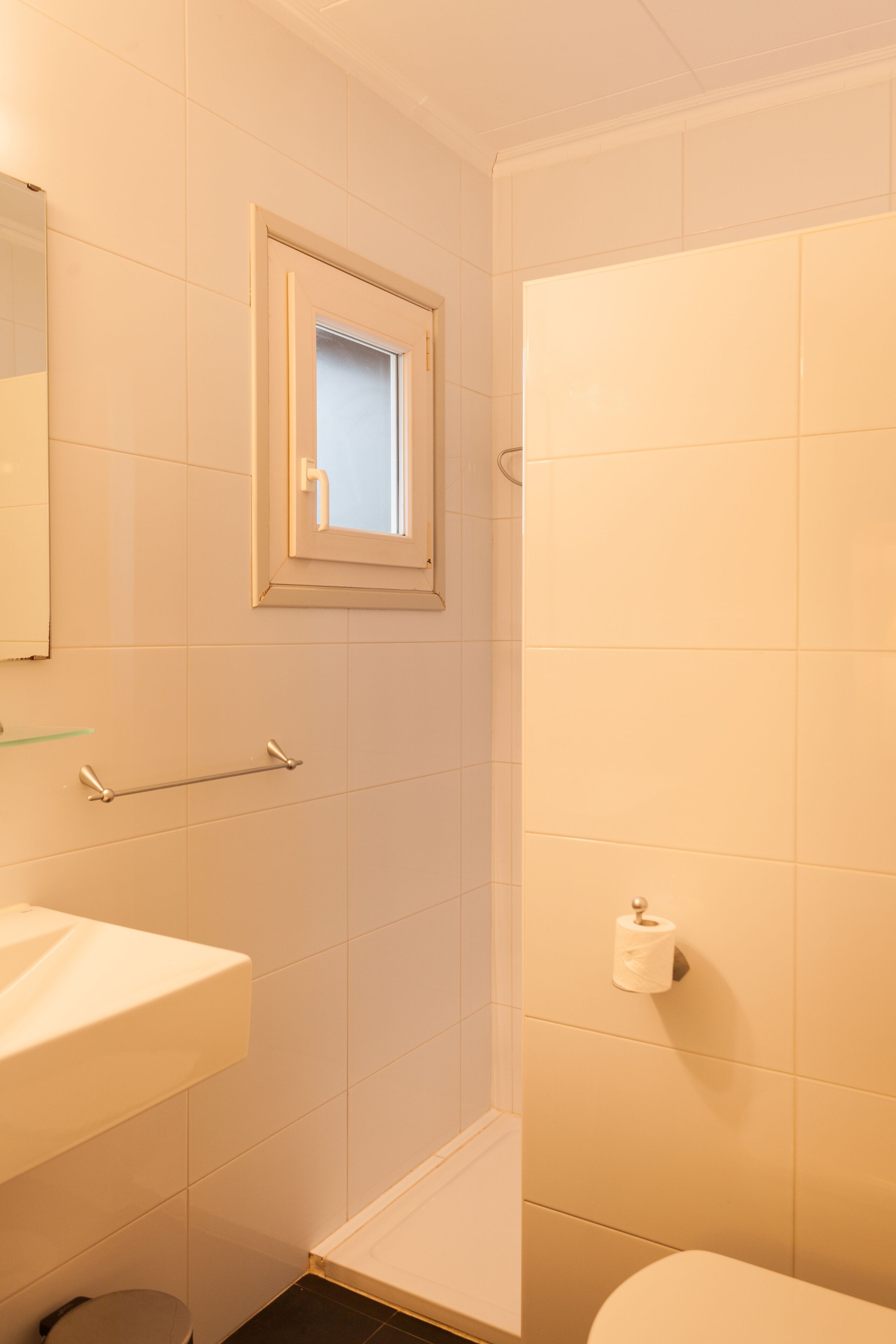 A bathroom with a toilet, sink, and a window.